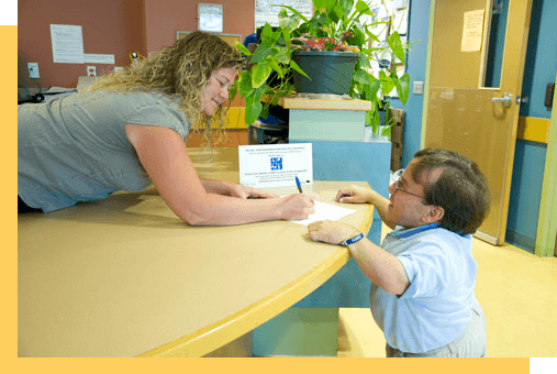 A person greeting another person at a desk