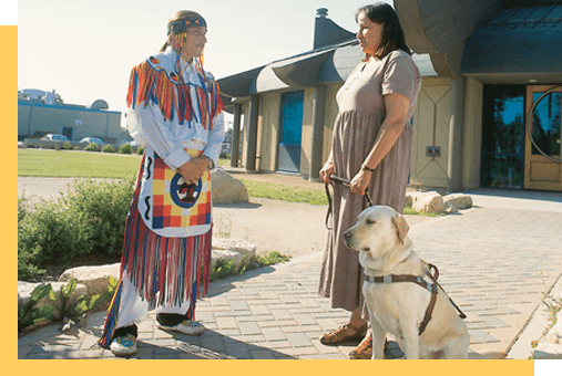 Two people standing outside with a support animal (dog)