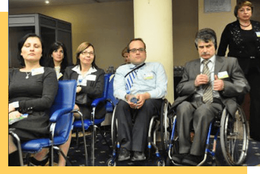 A group of people standing, sitting in chairs and wheelchairs